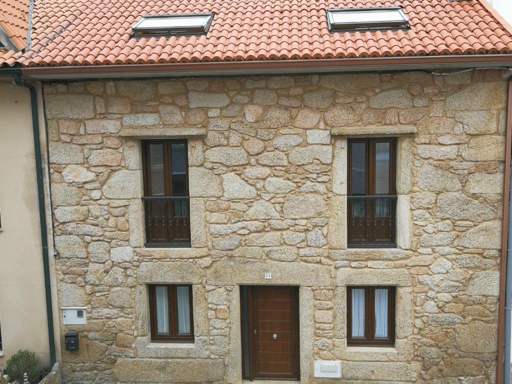 un edificio de piedra con 4 ventanas y techo rojo en Casa rural Camelle Casa dos avós en Camariñas