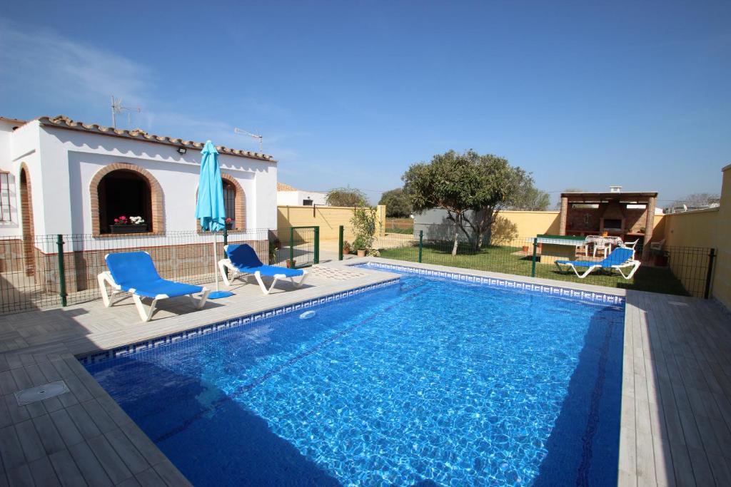 una piscina con sillas azules y una casa en Casa Melli en Conil de la Frontera