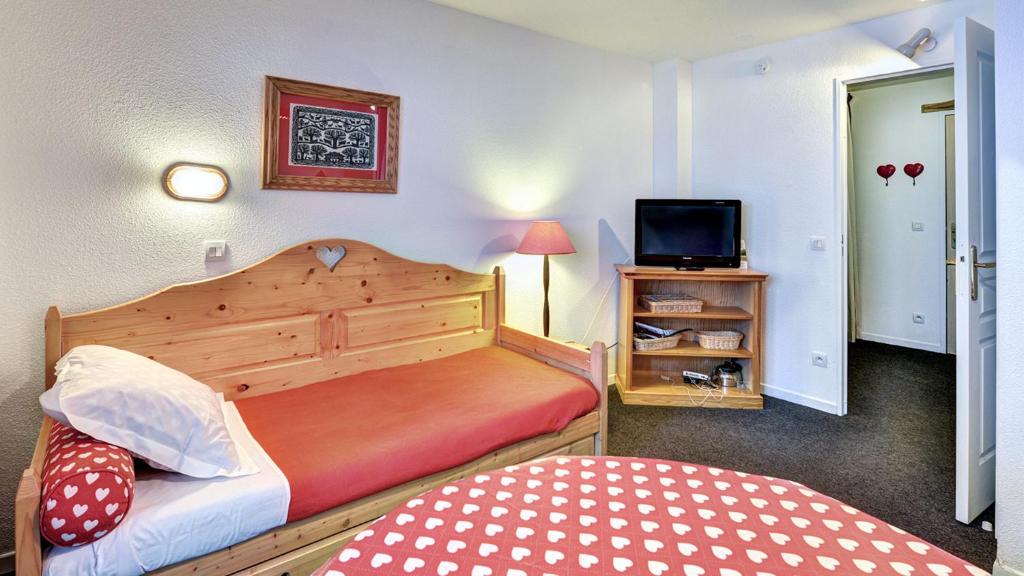 a small bedroom with two beds and a television at Vacancéole - Résidence Vega in Risoul