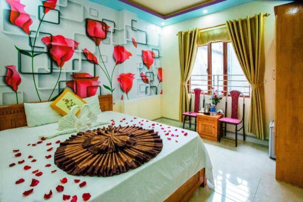 a bedroom with a bed with red flowers on it at Trang Toan Hotel in Cat Ba