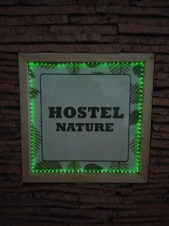 a sign on a brick wall with green lights at Hostel Nature in Zambujeira do Mar