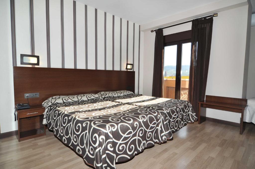 a bedroom with a black and white bed and a window at Hotel Ciudad de Plasencia in Plasencia