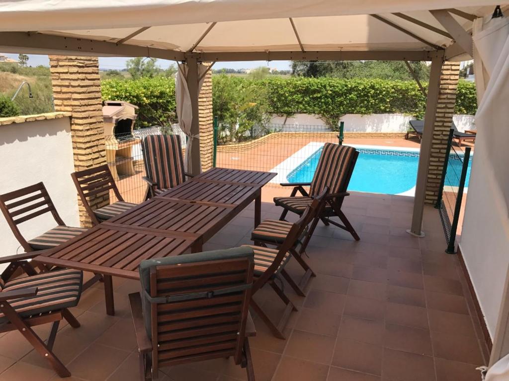 a wooden table and chairs under an umbrella next to a pool at Villa Mar - now with HEATED POOL! in Isla Canela
