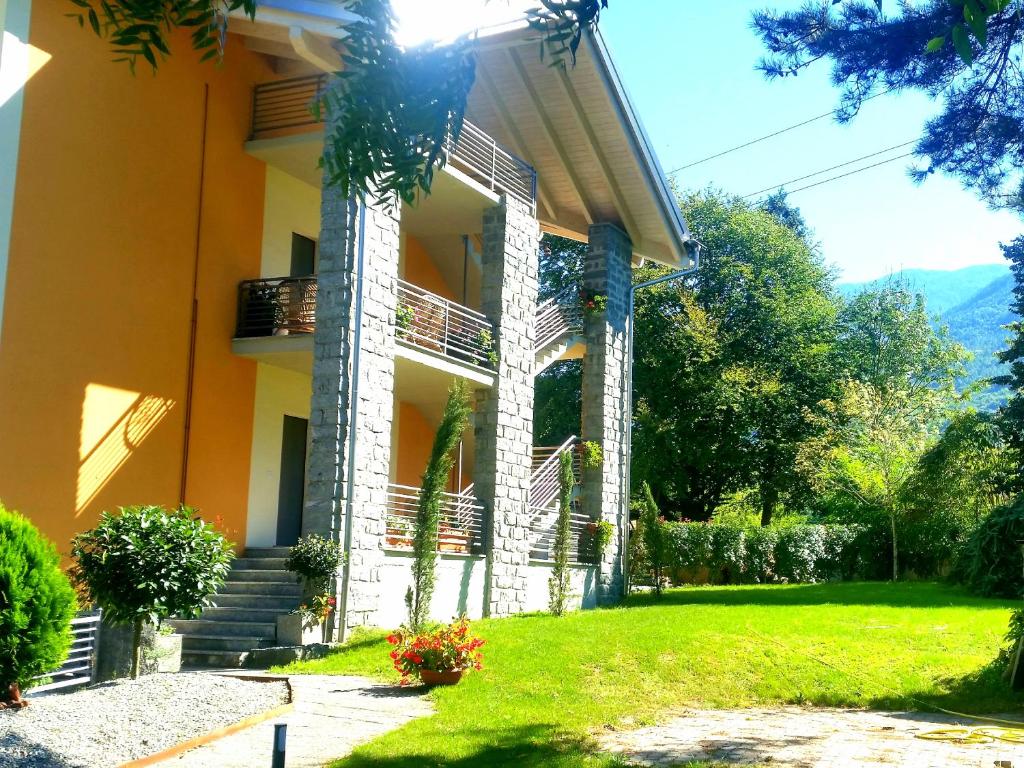 a yellow building with stairs and a grass yard at Villa Luisa Appartamenti Vacanze in Caiolo