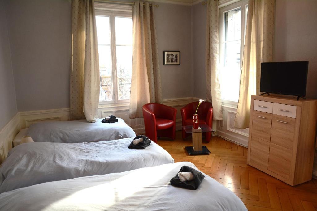 コルマールにあるLe cosy de la gareのベッド2台、テレビ、赤い椅子が備わる客室です。