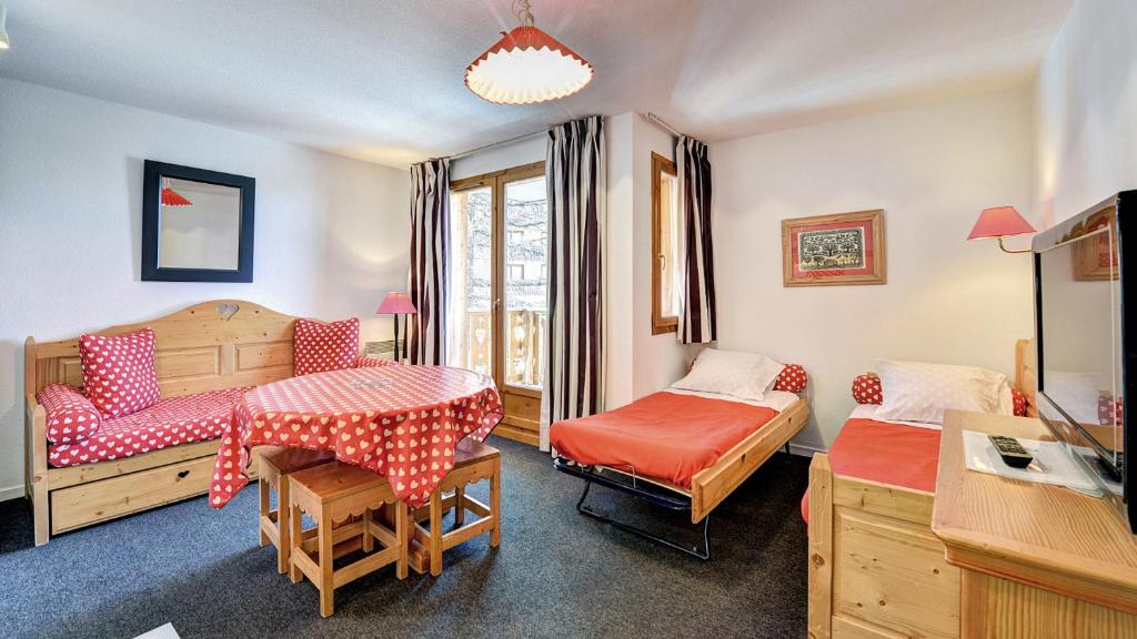 a room with two beds and a table and chairs at Vacancéole - Résidence Vega in Risoul