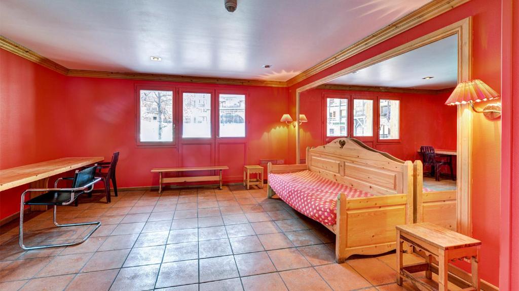 a bedroom with red walls and a bed and a desk at Vacancéole - Résidence Vega in Risoul