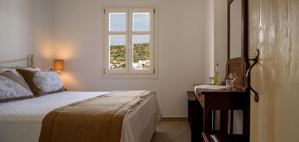 a bedroom with a bed and a window at Kimolos Houses in Kimolos