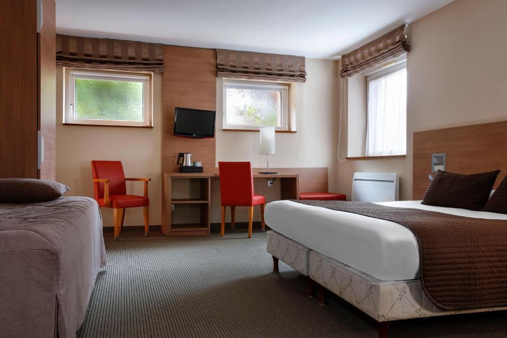 a hotel room with a bed and a desk and chairs at La Clef des Champs - Proche Colmar in Biesheim