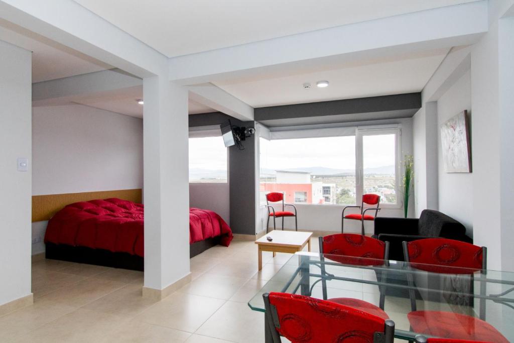 een slaapkamer met een rood bed en rode stoelen bij Infinity II Apartamentos in Ushuaia