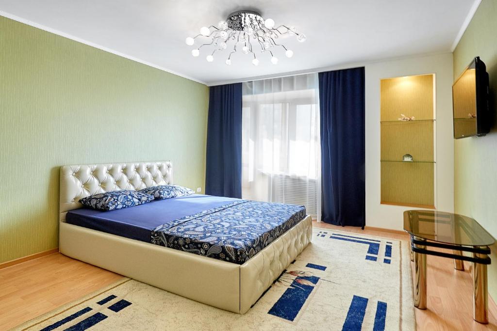 a bedroom with a bed and a chandelier at Апартаменты Абажур на Максима Горького in Kurgan
