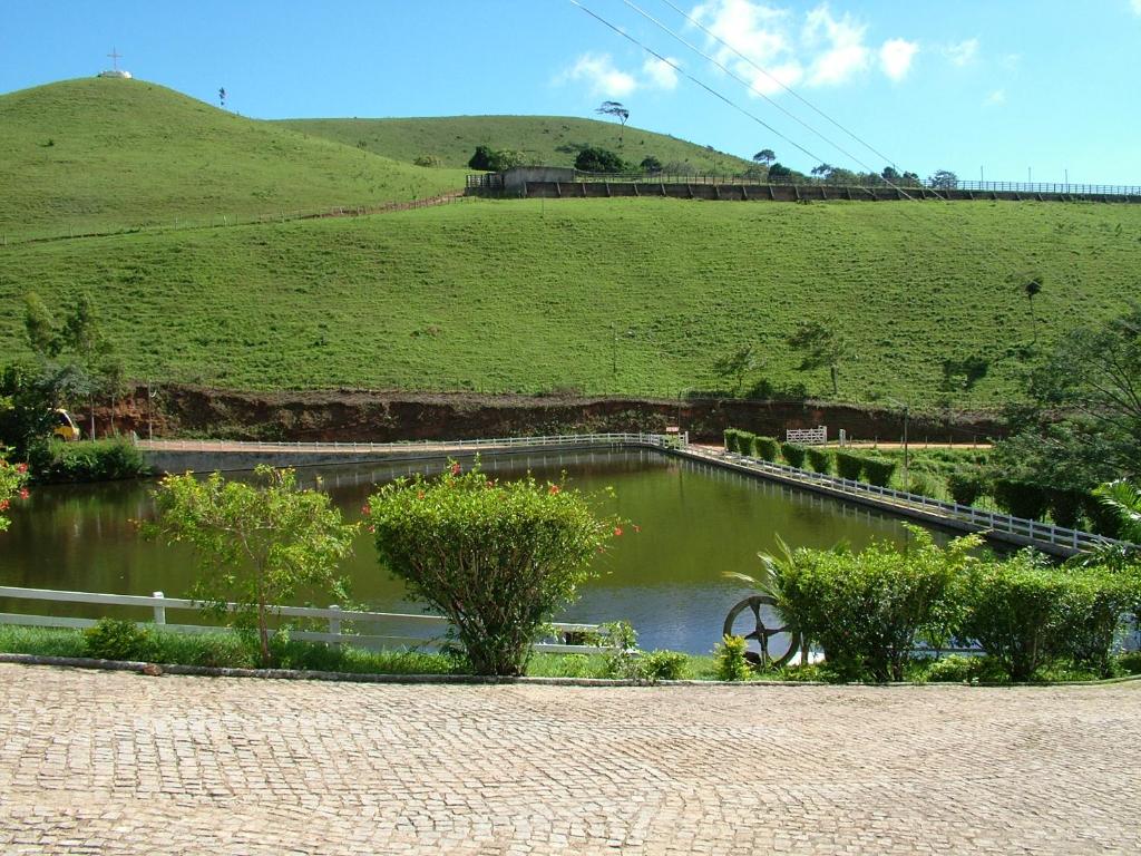 un étang avec un pont au milieu d'un champ dans l'établissement Hotel Fazenda Brejo, à Saloá