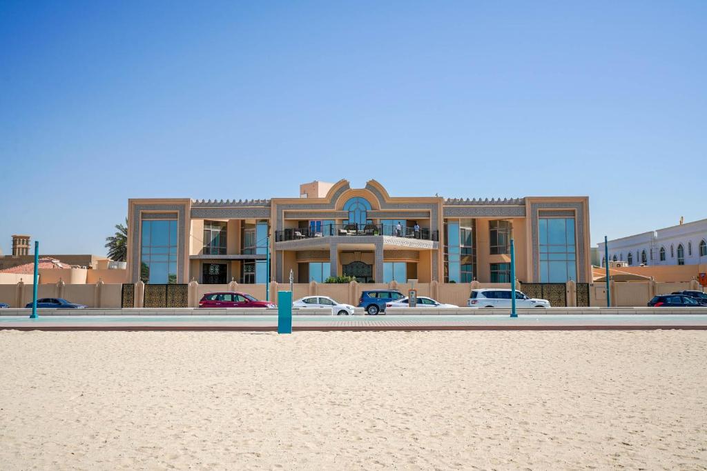 a building on the beach with cars parked in front of it at Hometown Apartments - Kite Palace - Lavish 7 Bedrooms villa on Kite Beach in Dubai
