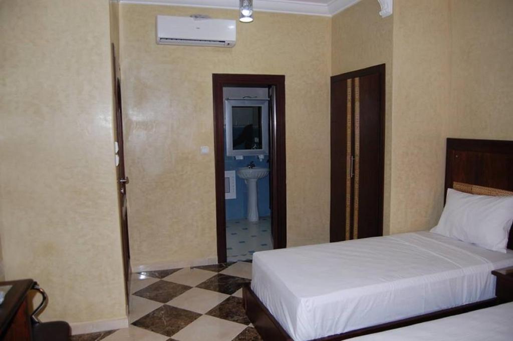 a bedroom with a bed and a bathroom with a sink at Hotel AMOUDOU فندق أمودو in Tiznit