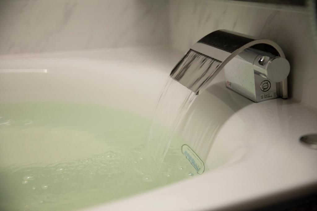 a faucet with water pouring into a sink at Miyajima Hanare no Yado IBUKU in Miyajima