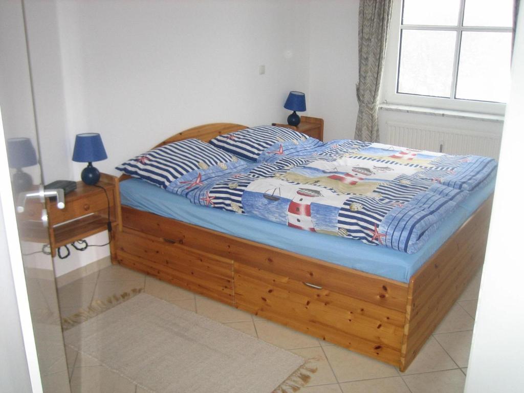 Schlafzimmer mit einem Bett mit einem Holzrahmen und einem Fenster in der Unterkunft FeWo ostseele - Julchen in Timmendorfer Strand