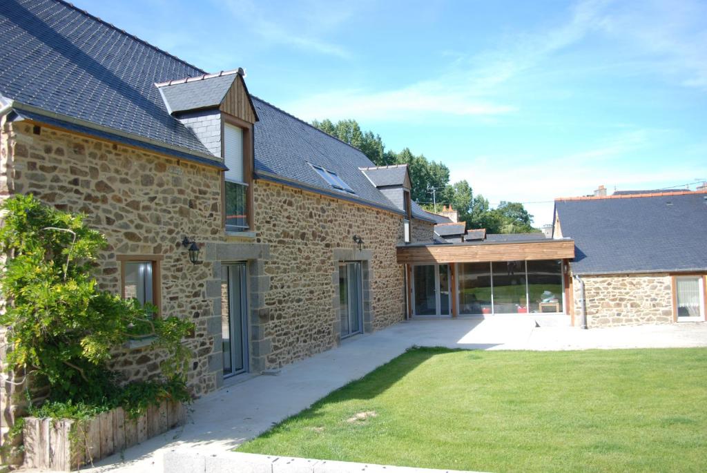 um edifício de tijolos com um relvado em frente em La Ferme du Chauchix em Lamballe