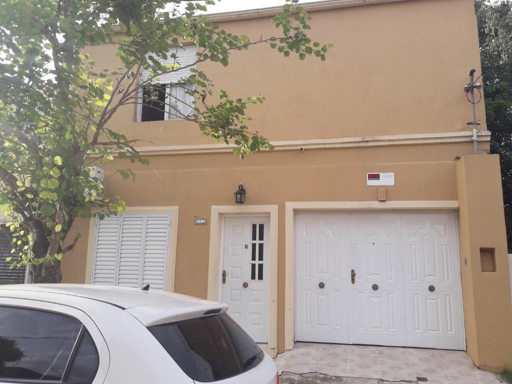 un coche blanco estacionado frente a una casa con dos puertas de garaje en Departamento céntrico completo en Gualeguaychú