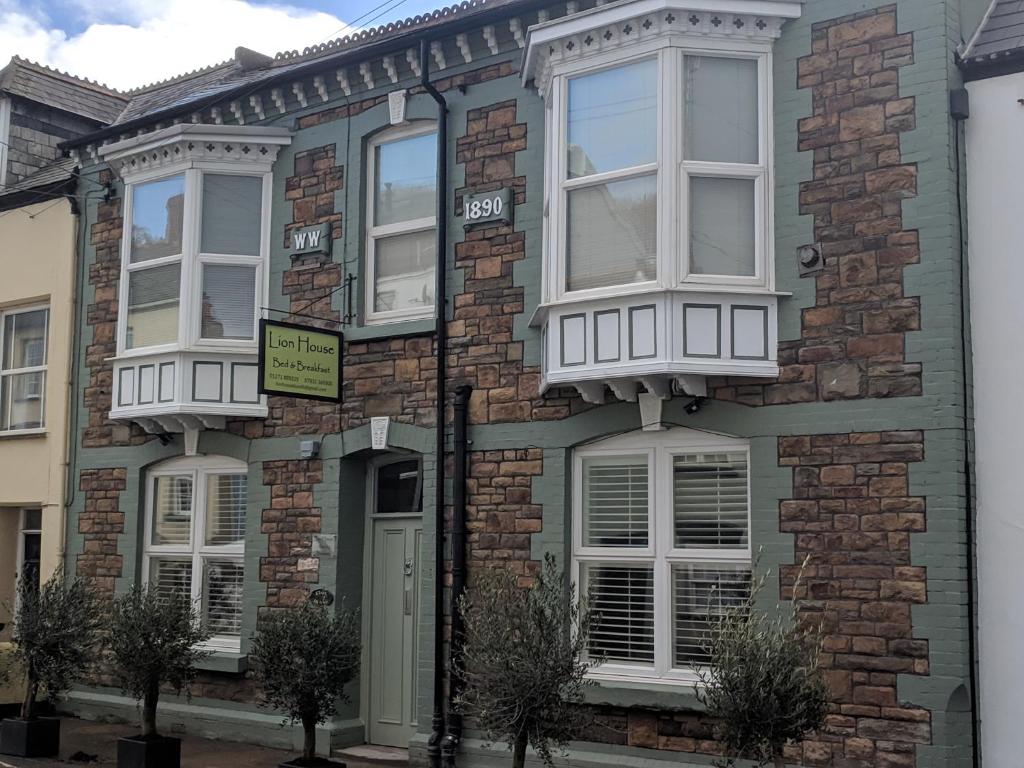 una casa de ladrillo con ventanas blancas en una calle en Lion House Bed & Breakfast with Restaurant, en Combe Martin