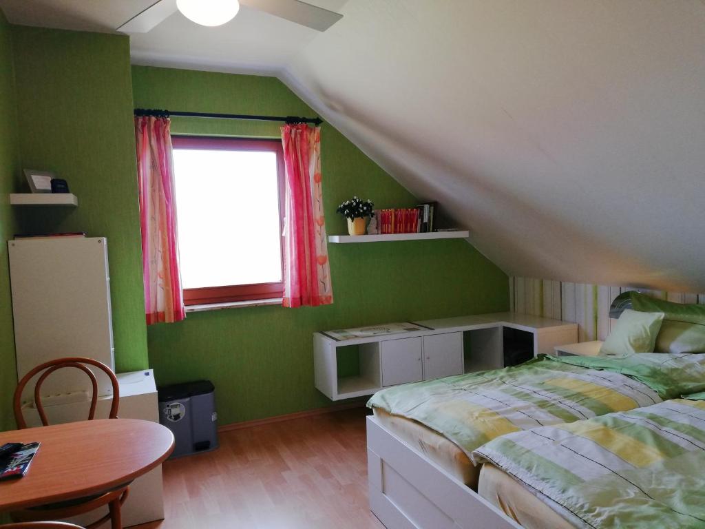 een slaapkamer met een bed, een tafel en een raam bij Privatzimmer mit Aussicht in Pirna