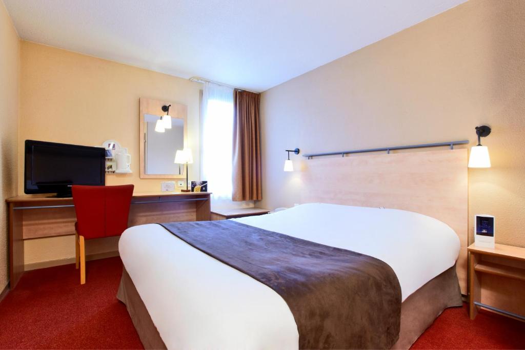 a hotel room with a large white bed and a red chair at Kyriad Beauvais Sud in Beauvais