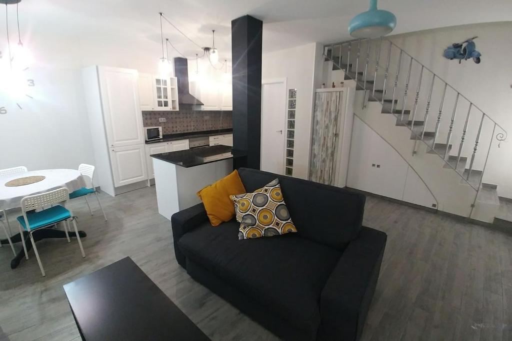 ein Wohnzimmer mit einem schwarzen Sofa und einer Küche in der Unterkunft Ca' els Ferros in Valencia