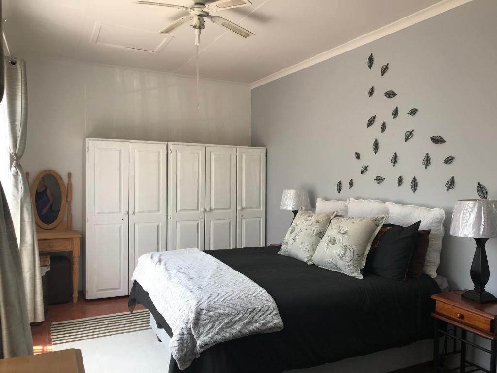 a bedroom with a bed with a black comforter at Contemporary Stay at Giraffe Cottage in Benoni