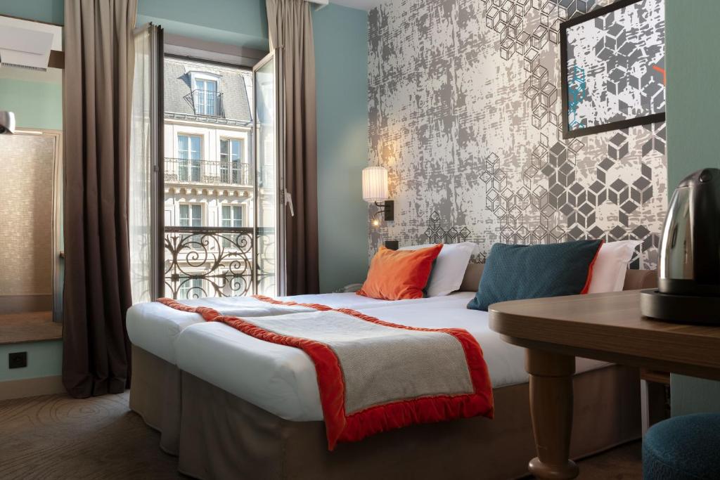 a bedroom with a large bed with a window at Hotel des Nations Saint Germain in Paris