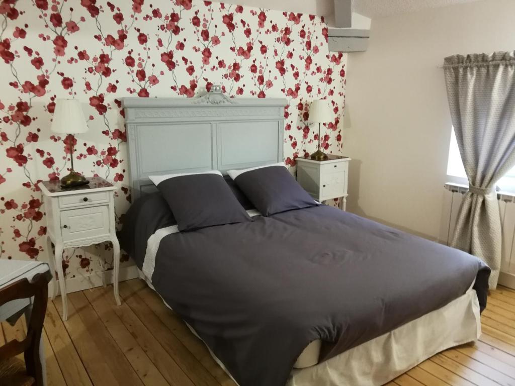 um quarto com uma cama grande e papel de parede floral vermelho em Le Dauphin em Chabeuil