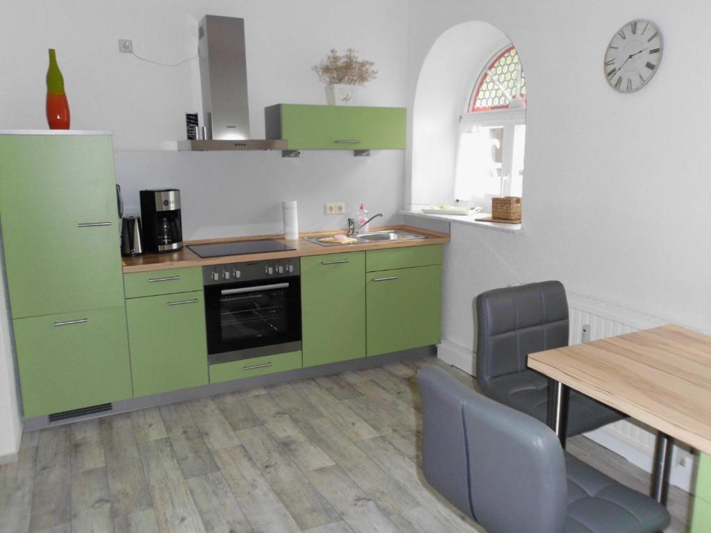 a kitchen with green cabinets and a table with chairs at Grüne Villa in Kromlau