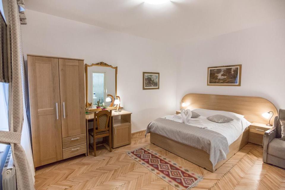 1 dormitorio con cama, escritorio y espejo en Pensiunea San Gennaro, en Miercurea-Ciuc
