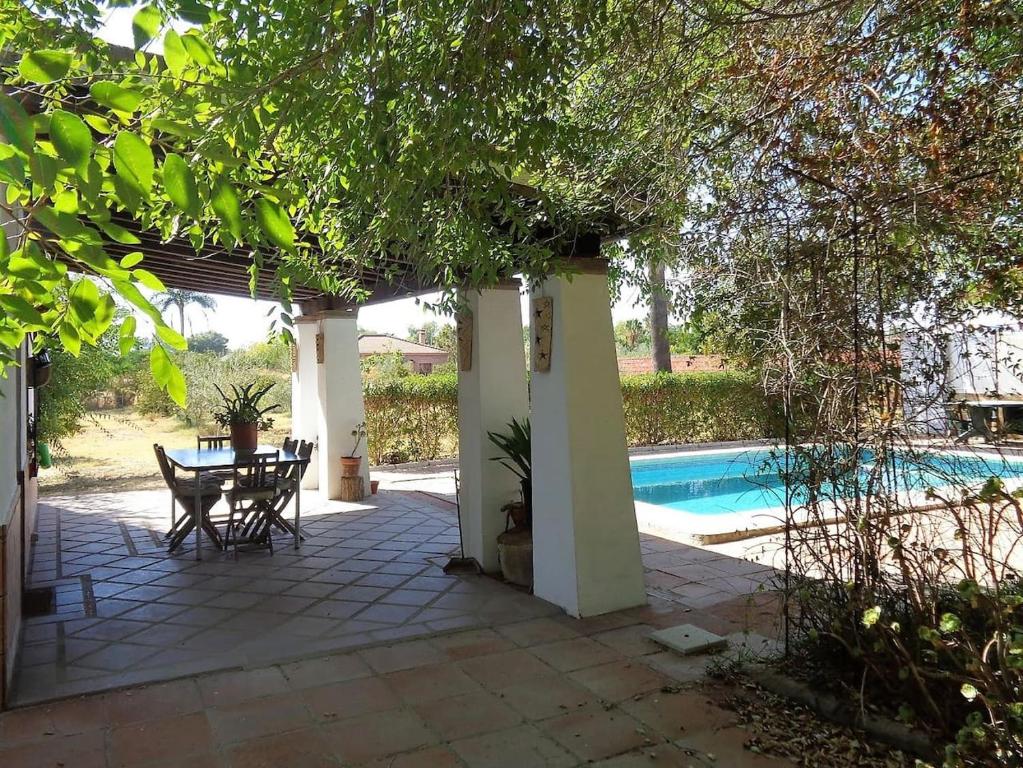 a patio with a table and chairs next to a pool at Casa los Jinetes in Carmona