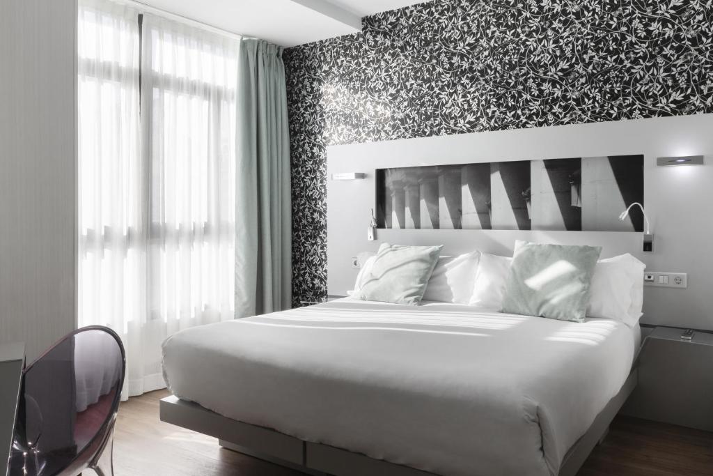 1 dormitorio con cama blanca y pared con detalles florales en Petit Palace Plaza Mayor en Madrid