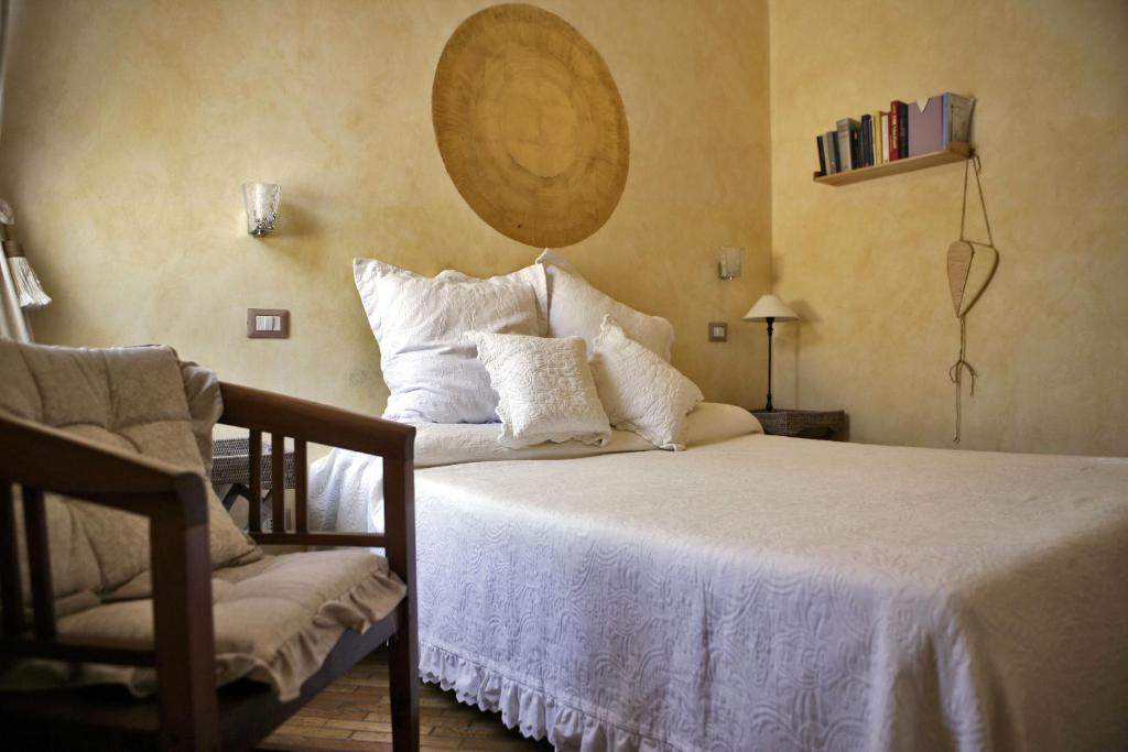 a bedroom with a bed with white pillows and a chair at Locanda di Mirandolina in Tuscania