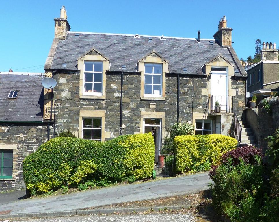 an old stone house with bushes in front of it at 6 Northgate Vennel, Peebles in Peebles