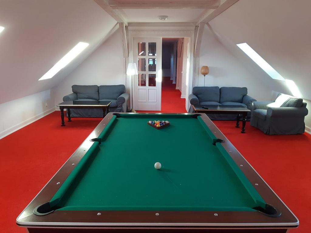 Attic game room featuring a pool table on red carpet, sofas and skylights along sloped ceiling.