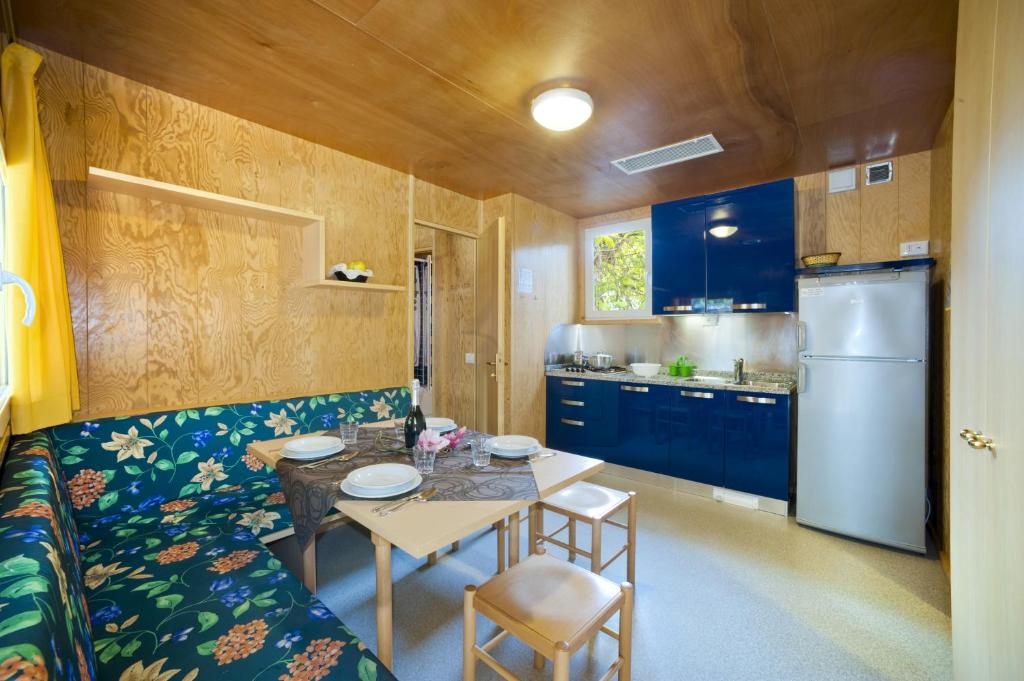 a small kitchen with a table and a refrigerator at Camping Village Capalonga in Bibione