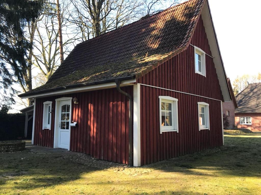 un granero rojo con una puerta blanca en Ferienhaus Moorhof, en Schneverdingen