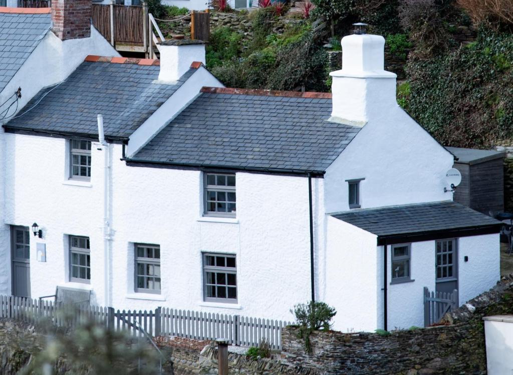 a white house with a lighthouse on a hill at Gulls Perch in Portloe