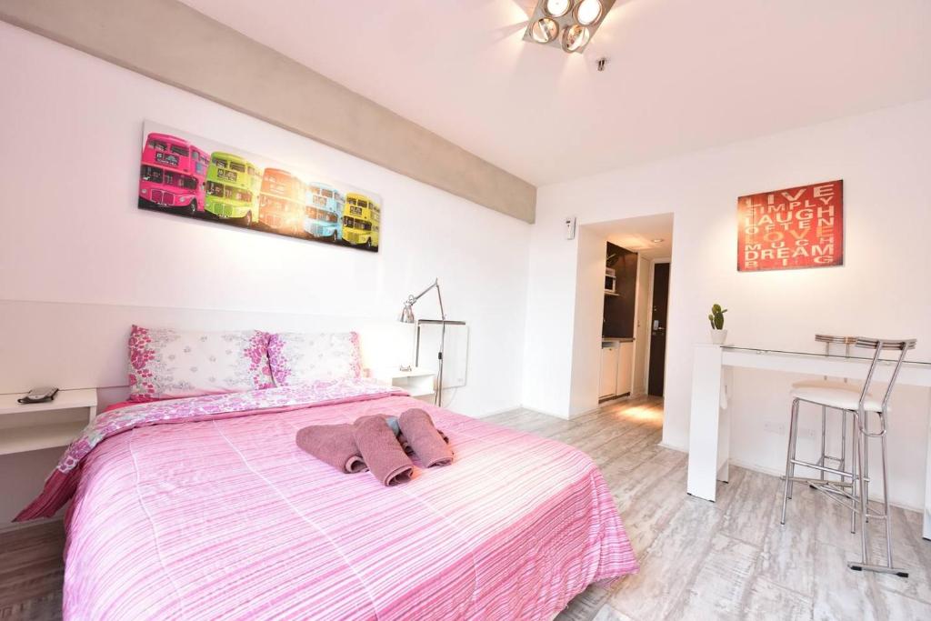 Un dormitorio con una cama rosa y blanca y una mesa en Studio Obelisco en Buenos Aires