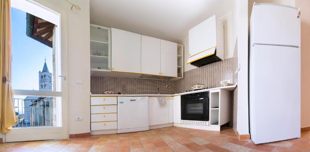 una cucina con elettrodomestici bianchi e una grande finestra di Appartamento di Bianca C. ad Assisi