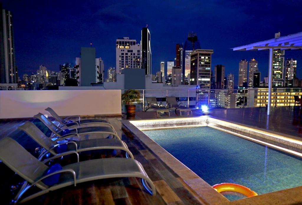 una piscina panoramica con sedie e uno skyline della città di notte di Victoria Hotel and Suites Panama a Città di Panama
