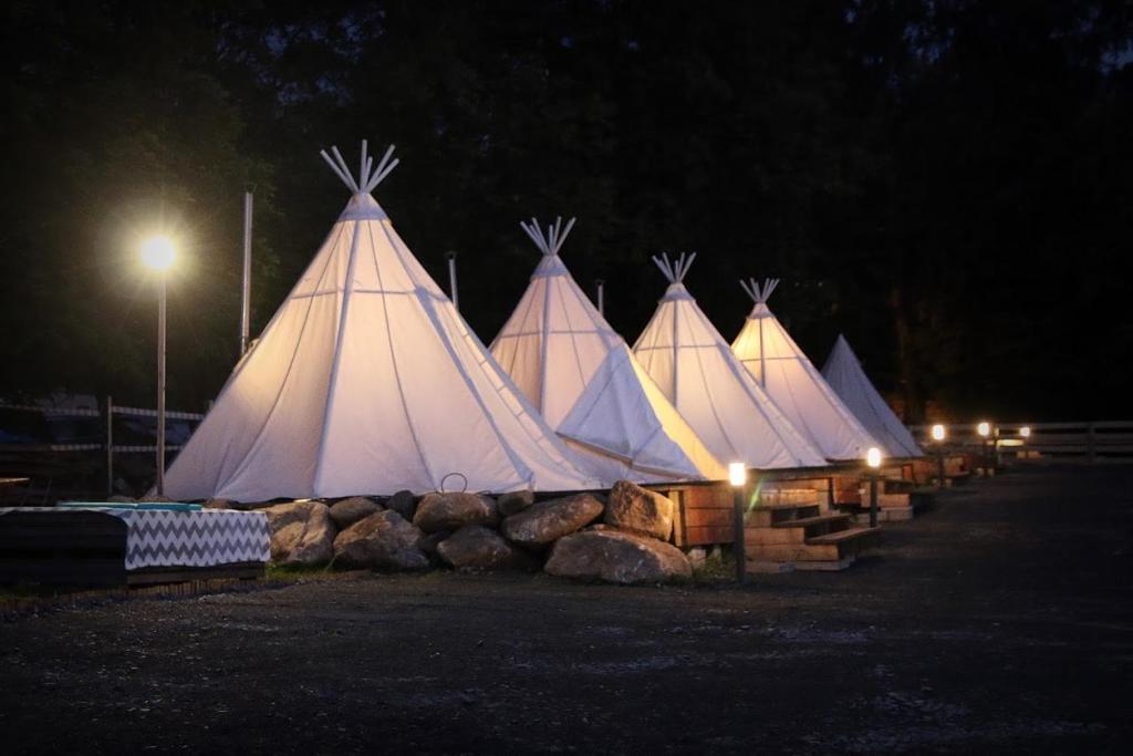 un grupo de tiendas blancas se iluminan por la noche en Fińska Wioska Kalevala en Borowice