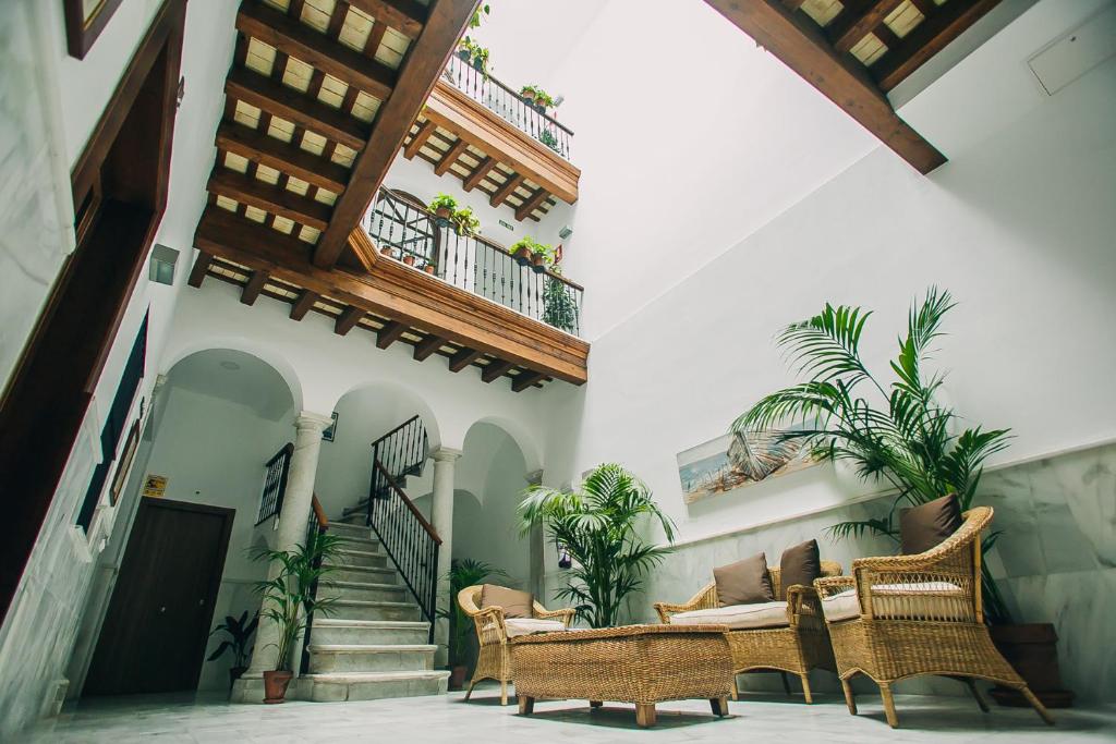 un patio con sillas de mimbre y escaleras en un edificio en Apartamentos casa palacio, en El Puerto de Santa María