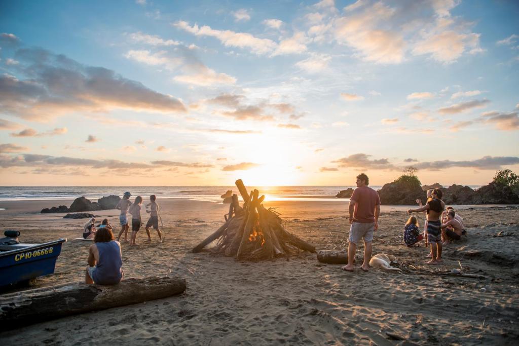 a group of people standing around a bonfire on a beach at The Humpback Turtle in El Valle