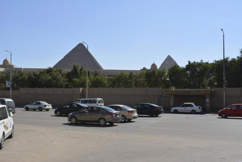 a parking lot with cars parked in front of pyramids at Pyramids Garden Motel in Cairo
