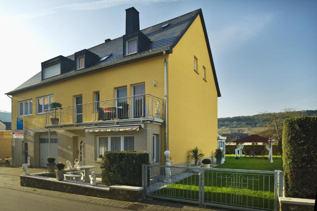 una grande casa gialla con una recinzione di fronte di Gästehaus Edith, 4-Sterne, 2-4 Personen a Trittenheim