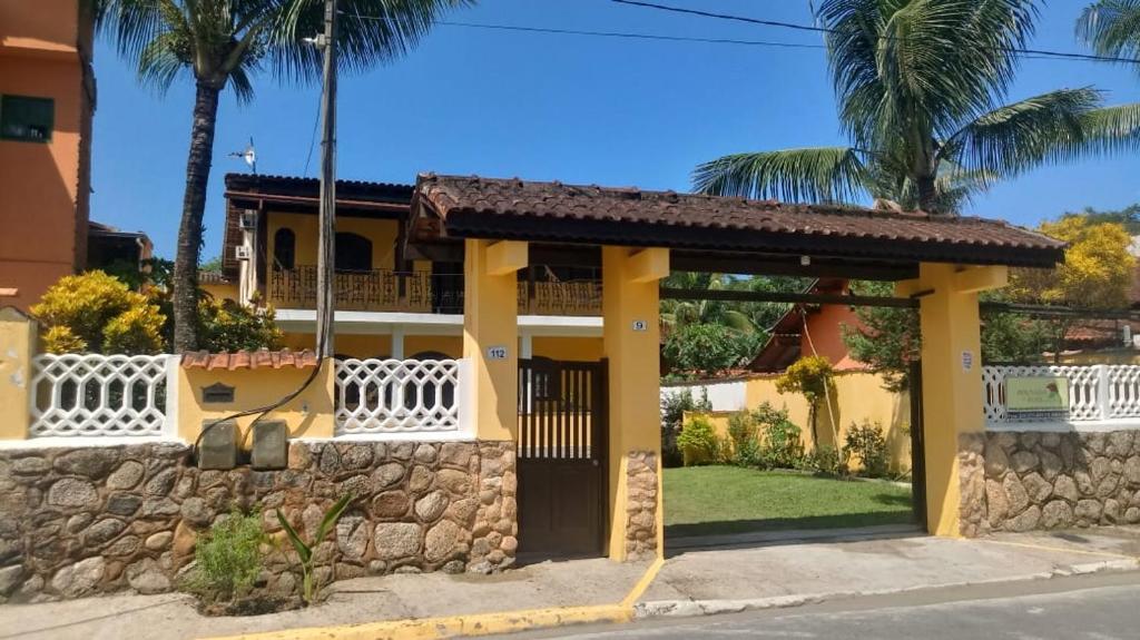 a yellow house with a stone wall and palm trees at Pousada da Rose Paraty in Paraty