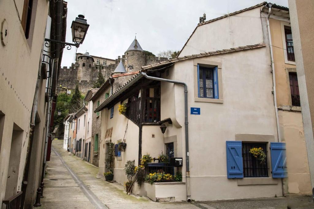 um beco com um edifício com um castelo ao fundo em La Petite Côte de la Cité em Carcassonne