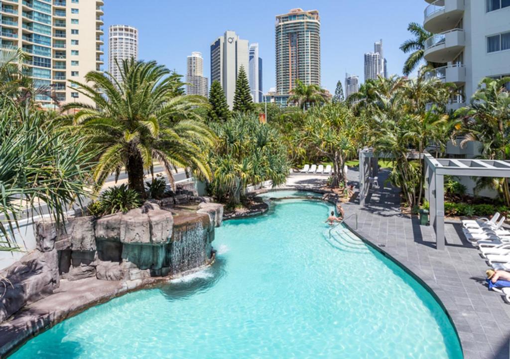 a pool at a resort with palm trees and buildings at Sovereign on the Gold Coast in Gold Coast